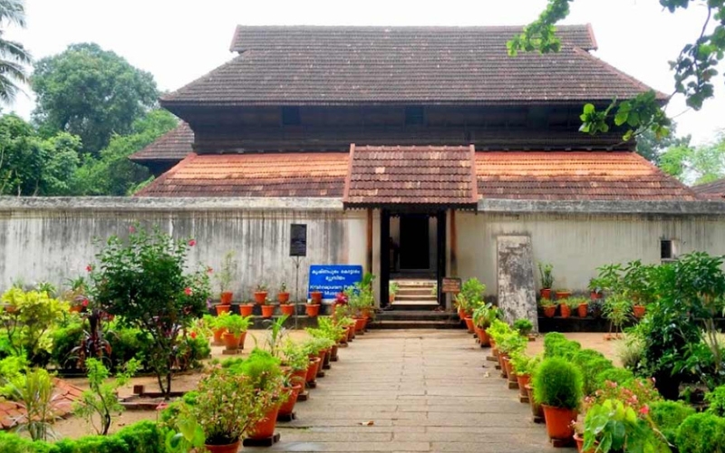 A majestic view of Krishnapuram Palace, a historic Kerala-style architectural marvel surrounded by lush gardens and featuring intricate woodwork.