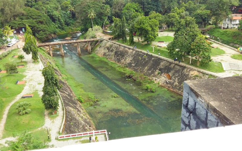 A scenic view of Malampuzha Dam and its beautiful gardens, with lush greenery, serene waters, and the backdrop of hills in Kerala.