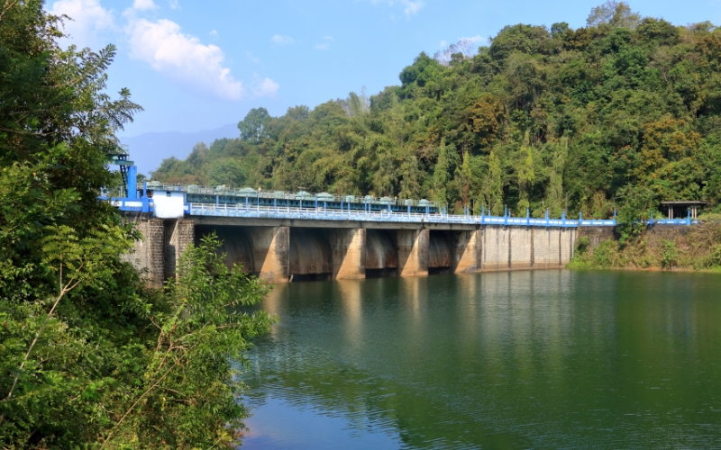 A scenic view of Mangalam Dam, surrounded by lush green hills and calm waters, creating a perfect nature retreat in Kerala.